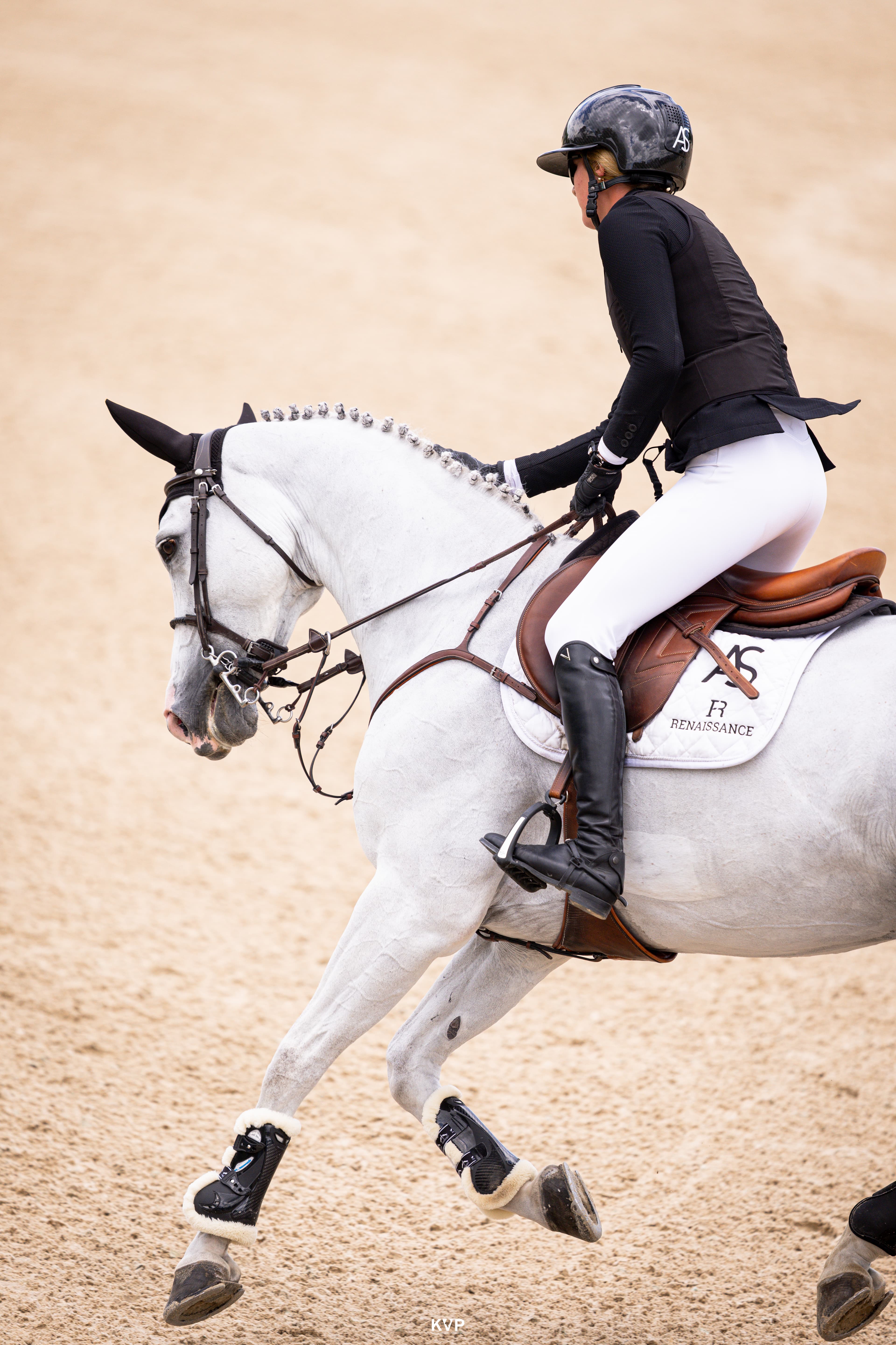A bay horse jumping powerfully over an oxer with Emma Marlowe in the irons